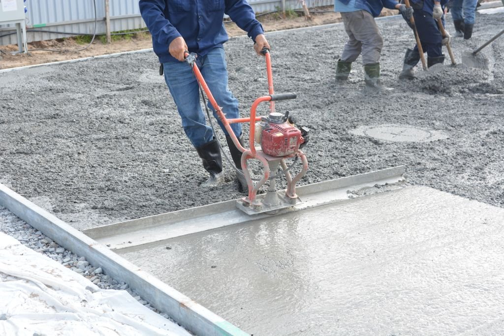 Team of construction workers using power tools to level freshly poured concrete on a building site in Norman, OK